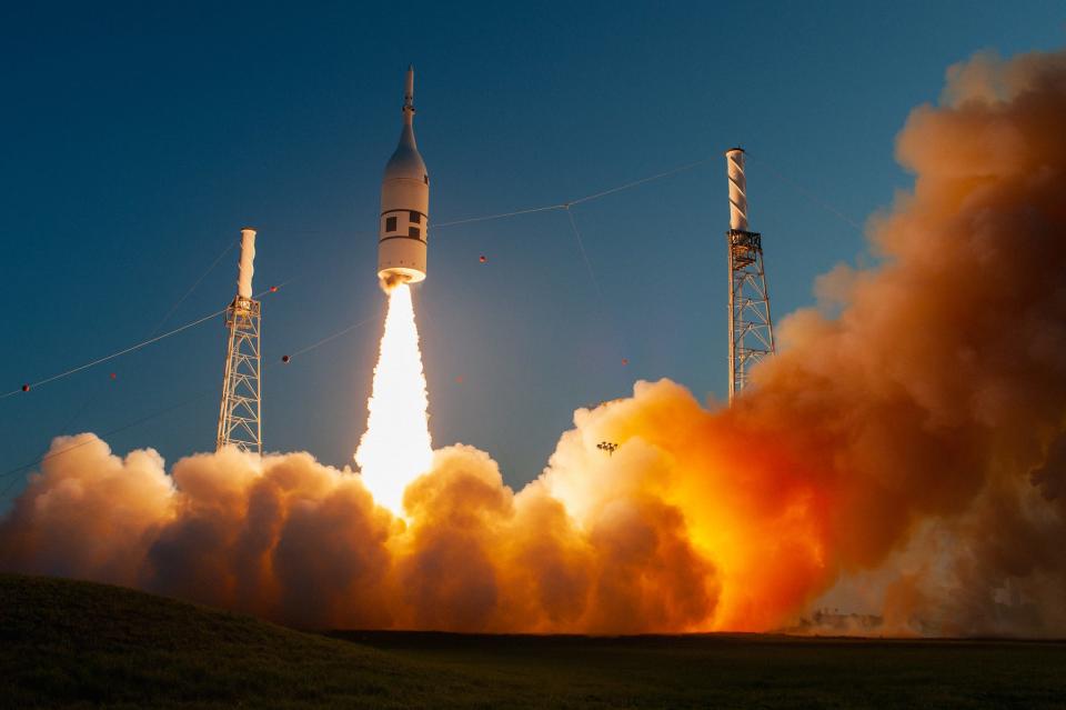 orion spaceship with pointy top fires engines lifting off making clouds of smoke