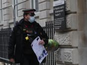 A policeman carries a well wisher's card and ballon outside St Bartholomew's Hospital where Britain's Prince Philip is being treated, in London, Wednesday, March 3, 2021. Prince Philip, the 99-year-old husband of Queen Elizabeth II, was transferred from King Edward VII's Hospital to St Bartholomew's Hospital to undergo testing and observation for a pre-existing heart condition as he continues treatment for an unspecified infection. (AP Photo/Alastair Grant)