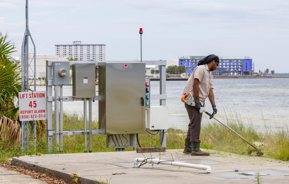 Panama City employee Xavier Houston cuts weeds around lift station 45 on West Beach Drive on May 24.