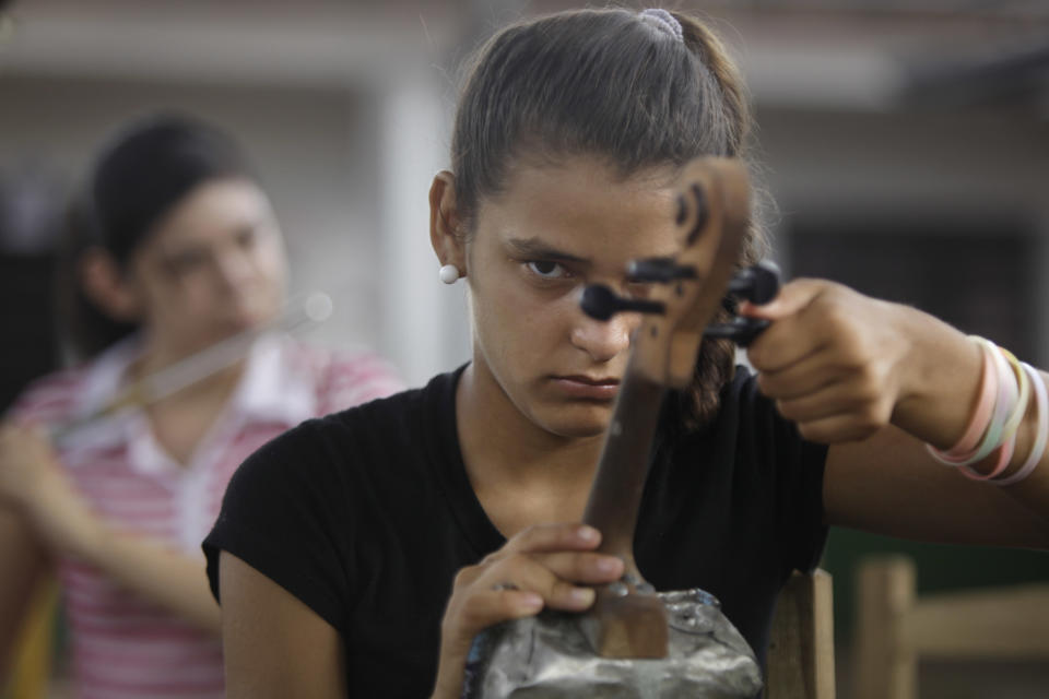 In this Dec. 11, 2012 photo, Tania Vera, 15, tunes her violin during a practice session with “The Orchestra of Instruments Recycled From Cateura” in Cateura, a vast landfill outside Paraguay's capital of Asuncion, Paraguay. I never thought my dreams would become reality,” said Vera, who lives in a wooden shack by a contaminated stream. Her mother has health problems, her father abandoned them, and her older sister left the orchestra after becoming pregnant. Tania, though, keeps to her goal of becoming a veterinarian as she keeps up with the music. (AP Photo/Jorge Saenz)