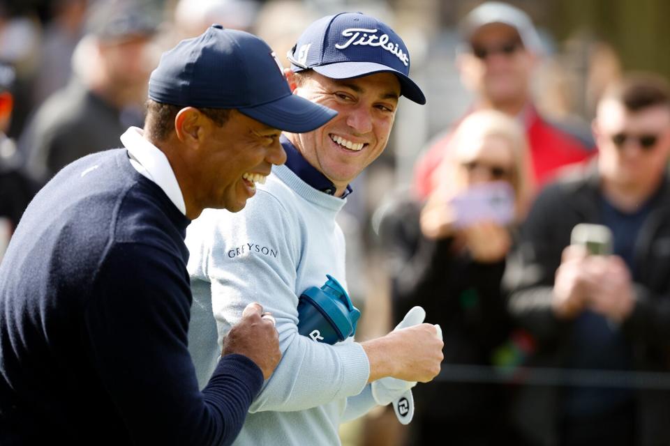 Tiger Woods of the United States and Justin Thomas of the United States walk across the ninth hole during the first round of the The Genesis Invitational at Riviera Country Club on February 16, 2023 in Pacific Palisades, California.