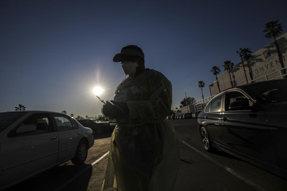 A woman walks beside cars holding a vaccine.