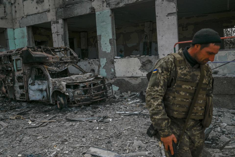 A Ukrainian soldier walks past a school hit by Russian rockets.