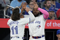 Toronto Blue Jays' Bo Bichette (11) celebrates after scoring with teammate Vladimir Guerrero Jr., right, during first-inning baseball game action against the Colorado Rockies in Toronto, Friday, April 12, 2024. (Frank Gunn/The Canadian Press via AP)