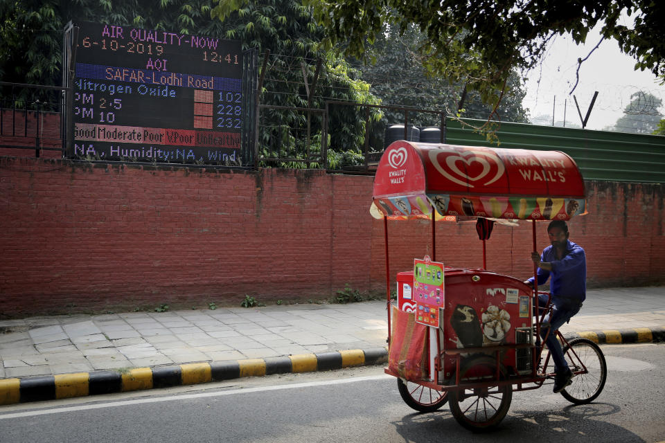 An ice-cream vendor rides past an air quality level board outside India Meteorological Department which shows condition of air as poor in New Delhi, India, Wednesday, Oct. 16, 2019. The Indian capital's air quality levels have plunged to "poor," a day after the government initiated stricter measures to fight chronic air pollution. The state-run Central Pollution Control Board's air quality index for New Delhi stood at 299 on Wednesday, about six times the recommended level. (AP Photo/Altaf Qadri)