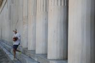 A tourist wearing a face mask against the spread of the new coronavirus, leaves Stoa Attalos in the ancient Agora archeological museum in Athens, Tuesday, Aug. 11, 2020. Greece’s culture ministry is closing down the Museum of the Ancient Agora, a major archaeological site in central Athens, for two weeks after a cleaner there was diagnosed with COVID-19. (AP Photo/Thanassis Stavrakis)