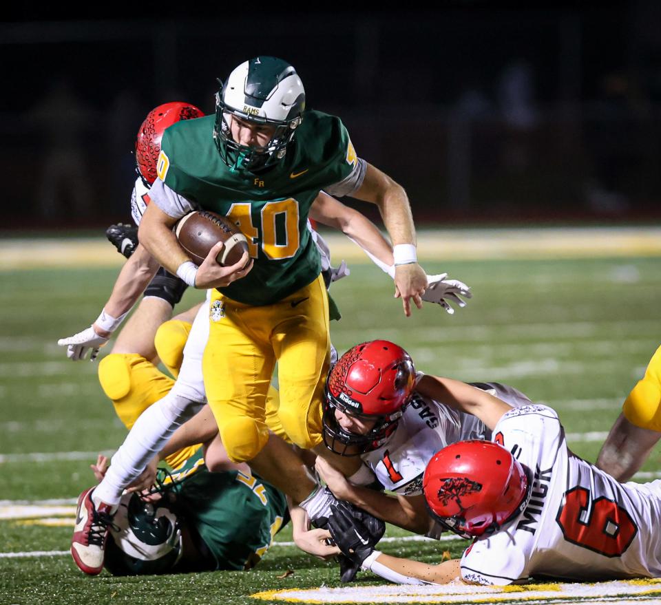 Brian Booms of Flat Rock runs past Milan defenders William Gaskell V, Gavin Mick (6) and CJ Fairbanks (13) during a 42-0 Flat Rock victory in the Division 5 state playoffs Friday night.