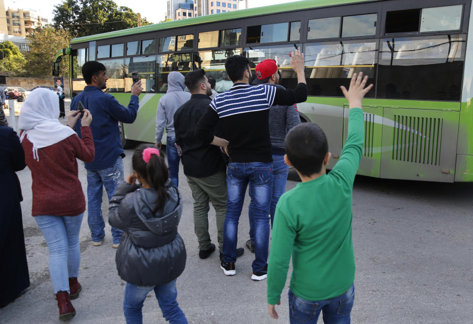 Syrian refugees who will stay in Lebanon wave goodbye to their relatives in a bus that will take them home to Syria, in Beirut, Lebanon, Tuesday, Dec. 3, 2019. Hundreds of Syrian refugees have returned home in the first batch to leave Lebanon since protests broke out in the country more a month ago. Lebanon is hosting about 950,000 registered Syrian refugees according to the U.N. refugee agency. The government estimates the true number of Syrian refugees in the country at 1.5 million. (AP Photo/Hussein Malla)