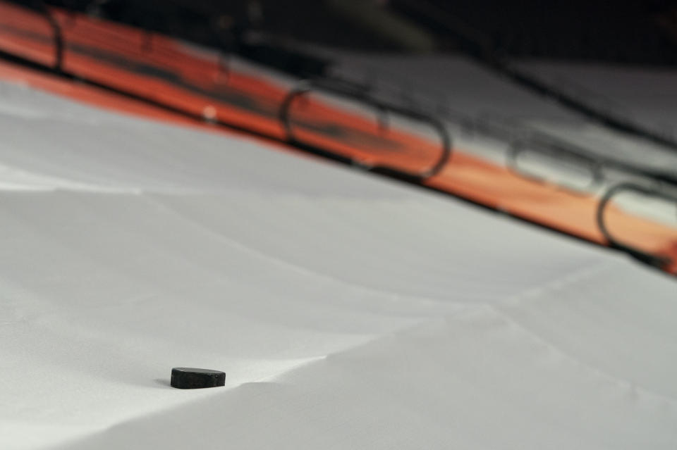 A puck lays on the tarp coving the seats prior to the first period of an NHL hockey game between the Pittsburgh Penguins and the Philadelphia Flyers, Wednesday, Jan. 13, 2021, in Philadelphia. (AP Photo/Chris Szagola)