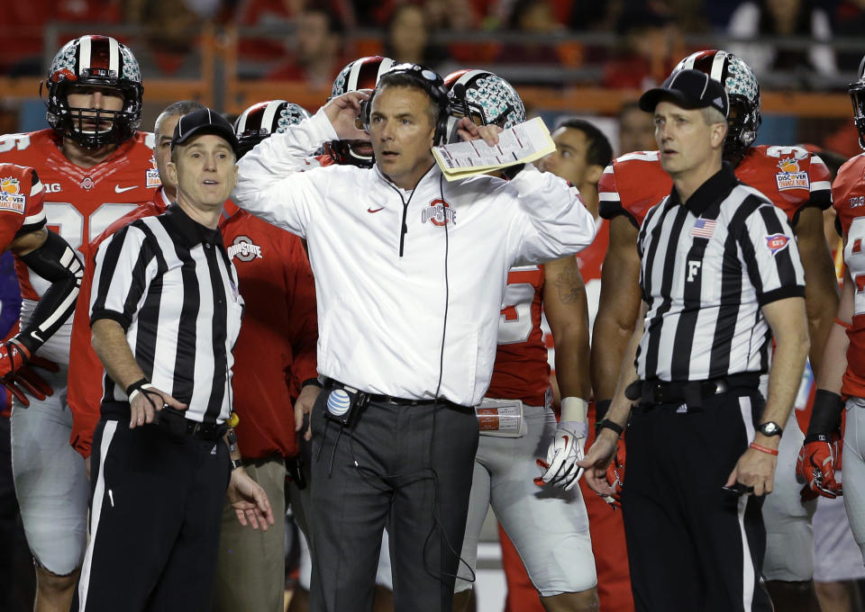 Ohio State coach Urban Meyer stands with officials as they wait for a ruling on the field during the first half of the Orange Bowl NCAA college football game against Clemson, Friday, Jan. 3, 2014, in Miami Gardens, Fla. (AP Photo/Lynne Sladky)