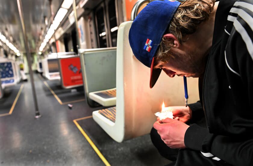 At right, seated on a subway train, a young man with dark blonde hair and a baseball cap smokes fentanyl