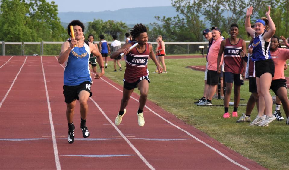 Teammates react in the infield as Mt. Markham Mustang Wil Lunny (left) passes the anchor runner for the Utica Academy of Science in the sprint to the finish of the four-by-400-meter relay at Section III's Class C-1 track and field championship meet Tuesday in Little Falls.