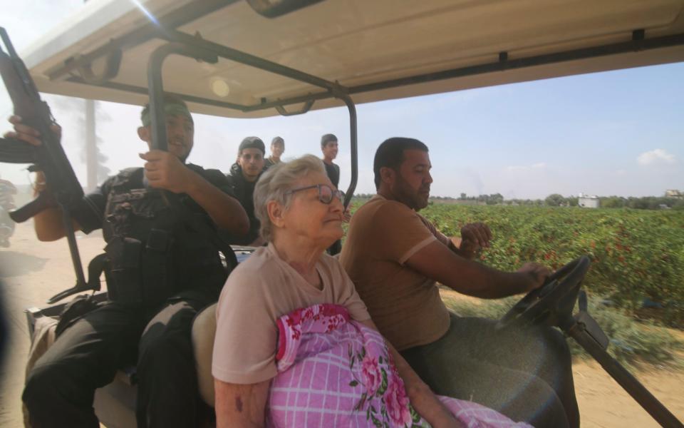 Eine ältere israelische Frau wirkt unnatürlich ruhig, als sie von bewaffneten Männern in einem Golfwagen in den Gazastreifen gefahren wird
