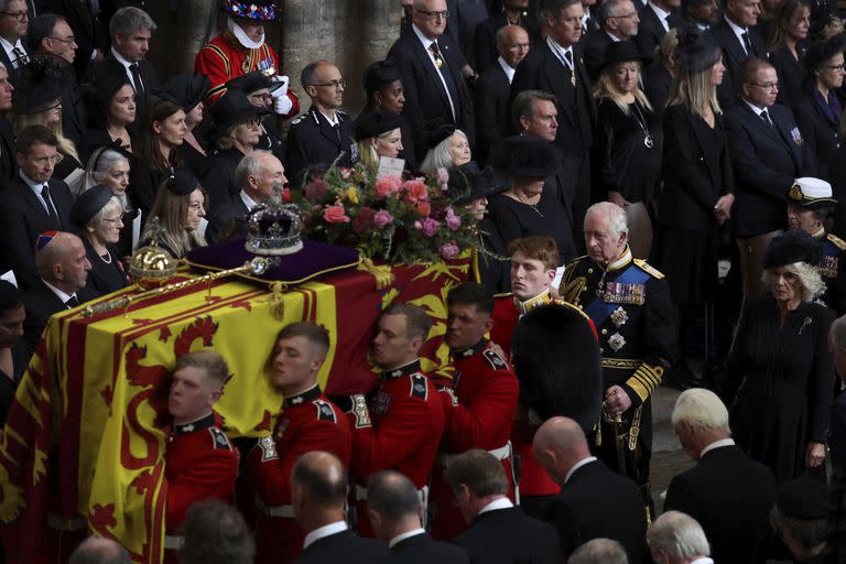 El féretro de la reina Isabel II es cargado mientras el rey Carlos III y la reina consorte Camila lo siguen tras su funeral en la Abadía de Westminster (Phil Noble/Pool Photo via AP)