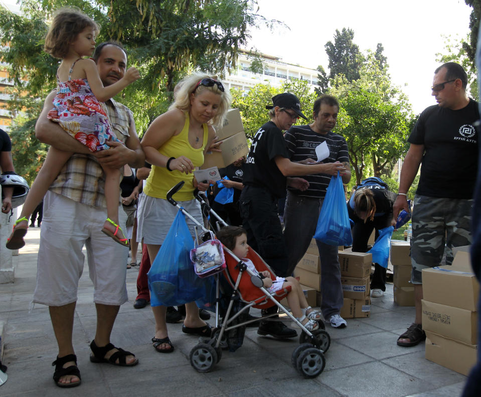 A family receives products from the members of Greece's extreme right Golden Dawn party at Athens' main Syntagma Square, opposite parliament, on Wednesday, Aug. 1, 2012. The volunteers checked ID cards of the public before handing Greek citizens food that included milk cartons, pasta, potatoes and olive oil. Golden Dawn won 18 seats in the 300-seat parliament in June general elections. Senior party members openly support a policy of granting Greek citizenship based on racial identity. The party has stepped up its charity effort as Greece is suffering through a fifth year of recession, with rapidly rising rates of poverty and unemployment. (AP Photo/Thanassis Stavrakis)