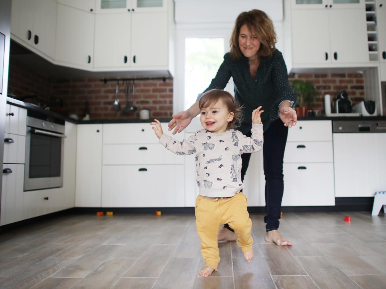 First steps of a 1 year old baby boy in the kitchen