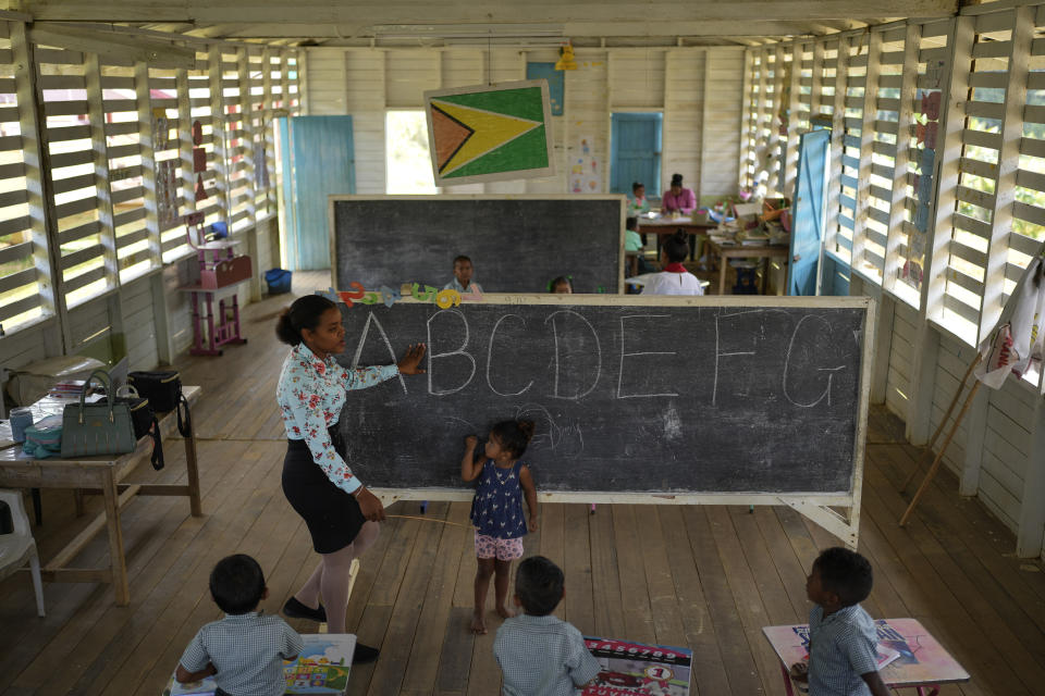 A teacher reviews the alphabet with her Amerindian students during a class in Chinese Landing, Guyana, Monday, April 17, 2023. Guyana has some 78,500 Amerindians who represent nearly 10% of the country’s population. They live in more than 240 communities that often are home to large deposits of gold such as Chinese Landing. (AP Photo/Matias Delacroix)