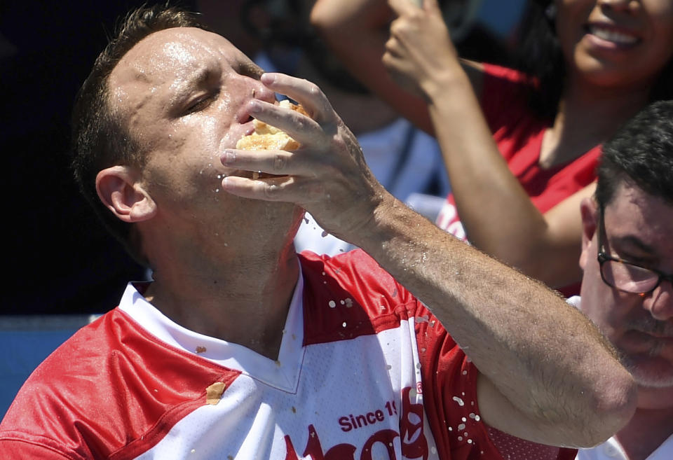 Joey Chestnut stuffs his mouth with hot dogs during the men's competition of Nathan's Famous July Fourth hot dog eating contest, Thursday, July 4, 2019, in New York's Coney Island. (AP Photo/Sarah Stier)