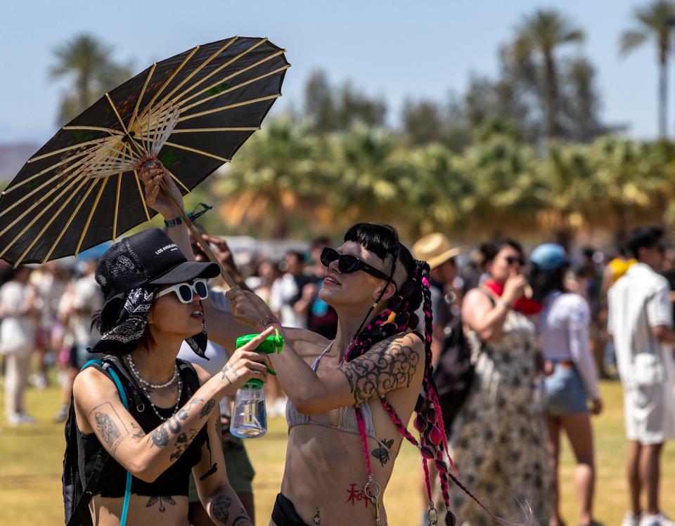 A festivalgoer raises a parasol for shade during the Coachella Valley Music and Arts Festival in Indio, Calif., Friday, April 12, 2024.