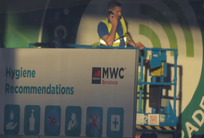 Employee is pictured next to a banner with information of MWC20 (Mobile World Congress) in Barcelona