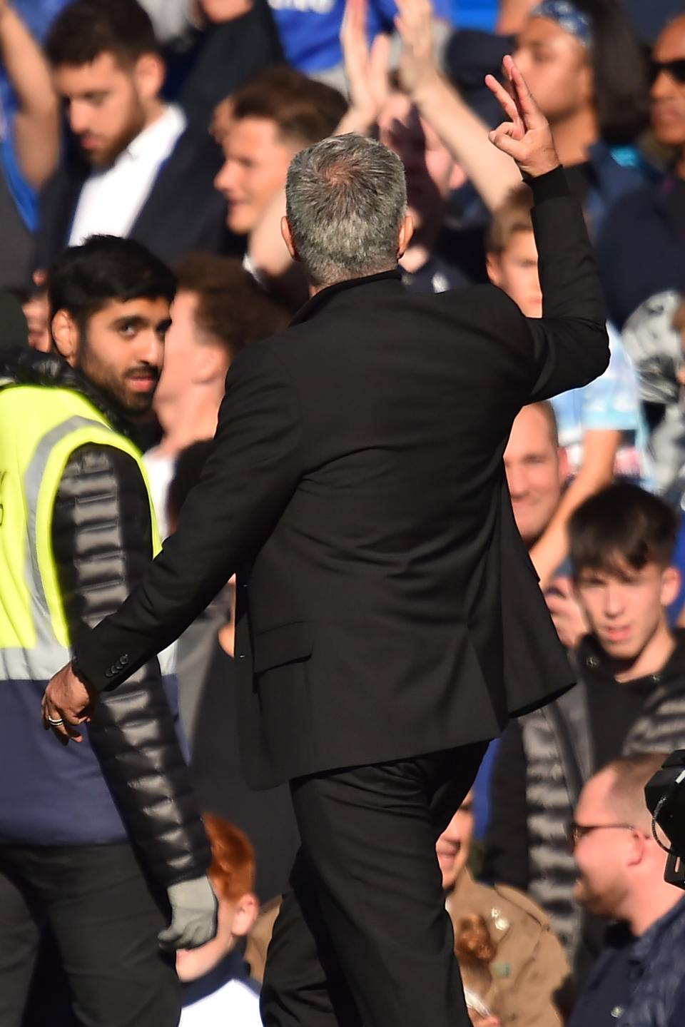 Manchester United’s Portuguese manager Jose Mourinho holds up three fingers, indicating the three titles he won (Photo by Glyn KIRK / AFP