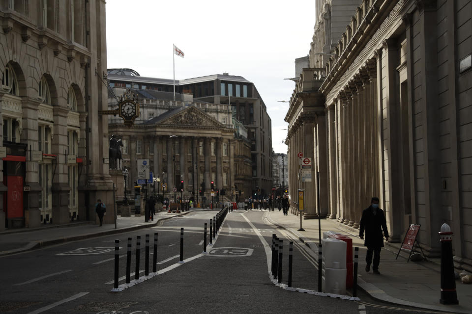 People walk past the Bank of England, at right, in the City of London financial district of London, during England's third coronavirus lockdown, Tuesday, Feb. 23, 2021. British Prime Minister Boris Johnson announced on Monday a slow easing of one of Europe's strictest pandemic lockdowns, with non-essential shops and hairdressers due to reopen April 12. (AP Photo/Matt Dunham)