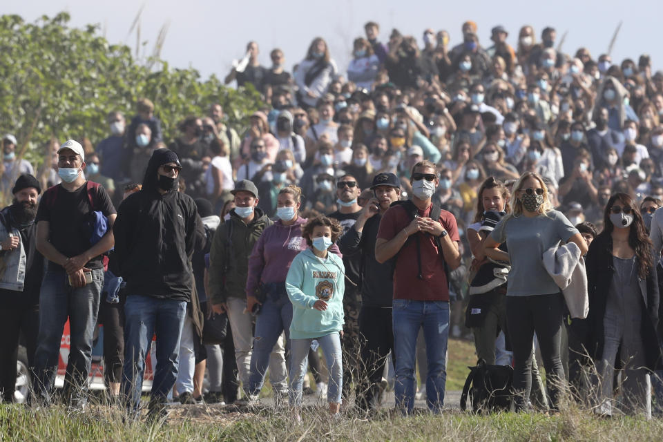 Crowds gather trying to get a view of the waves after police blocked access to the cliffs where too many people were already watching a tow surfing session at Praia do Norte or North Beach in Nazare, Portugal, Thursday, Oct. 29, 2020. A big swell generated earlier in the week by Hurricane Epsilon in the North Atlantic, reached the Portuguese west coast drawing big wave surfers to Nazare and thousands of spectators as well. (AP Photo/Pedro Rocha)