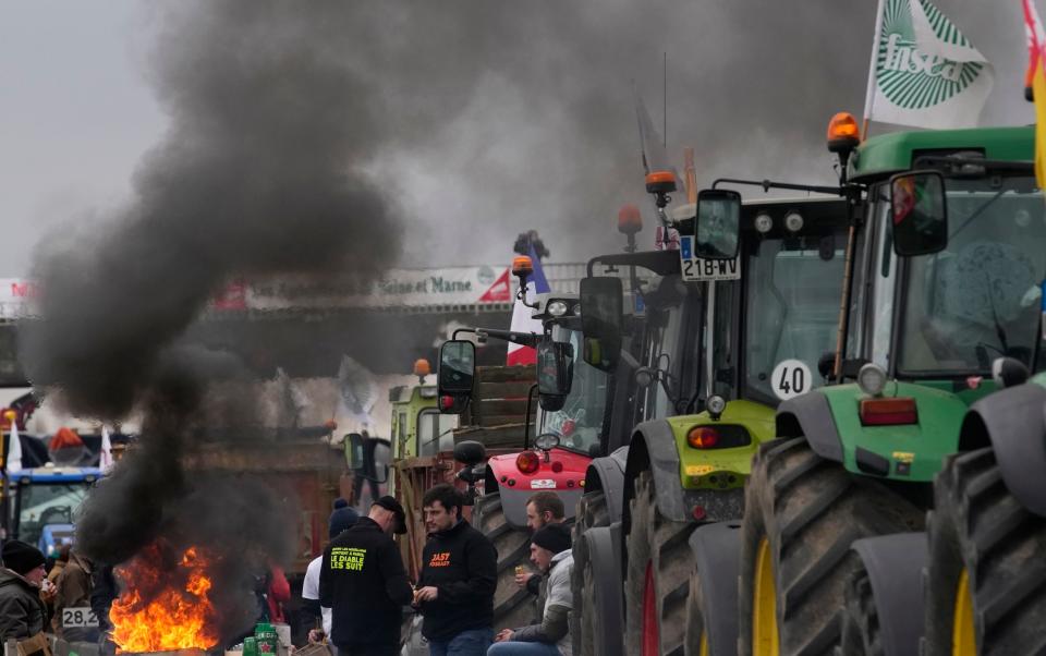 A fire burns as farmers block a highway in Jossigny, east of Paris