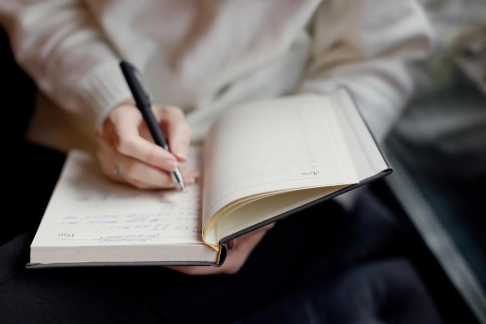 Caucasian woman writing in notebook indoors at cozy cafe