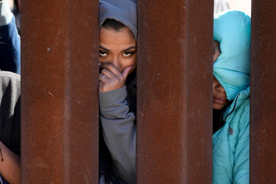 Migrants waiting to apply for asylum between two border walls look through the wall on May 11, 2023, in San Diego. Pandemic-related U.S. asylum restrictions, known as Title 42, expired.