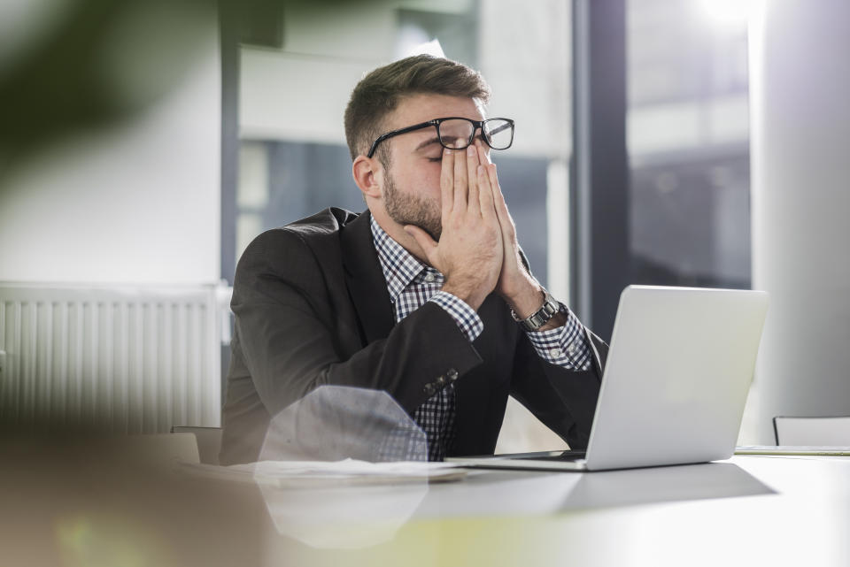 a man looking frustrated sitting at his laptop