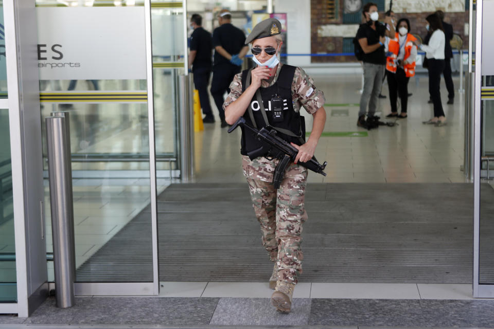 A female police officer adjust her mask as she guards at Cyprus' main airport in Larnaca, on Tuesday, June 9, 2020. Cyprus re-opened its airports on Tuesday to a limited number of countries after nearly three months of commercial air traffic as a result of a strict lockdown aimed at staving off the spread of COVID-19. (AP Photo/Petros Karadjias)