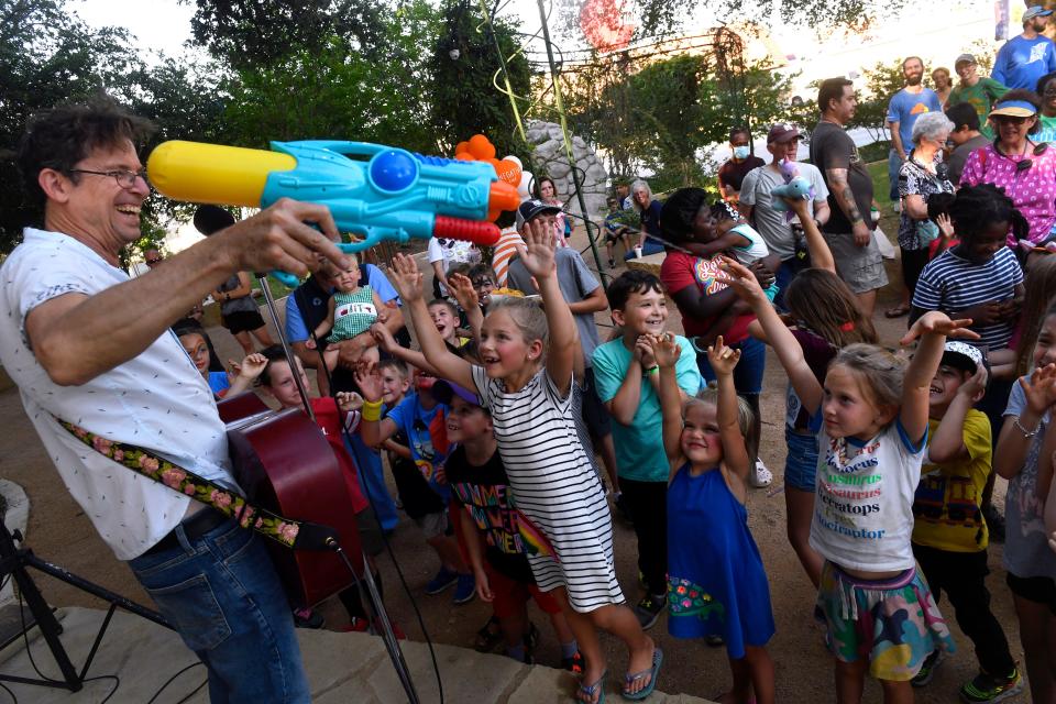 Musician Joe McDermott sprays his young audience with a squirt gun at Adamson-Spalding Storybook Garden after Thursday's Children's Art & Literacy Festival's Storybook Parade.