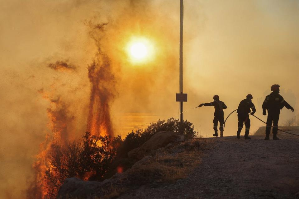 Firefighters try to extinguish a wildfire burning in Saronida, near Athens on Monday (REUTERS)