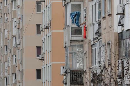 A woman hauls dust from a bed cover from the window of a communist era block of flats in Bucharest, Romania, November 23, 2016. Picture taken November 23, 2016. Inquam Photos/Octav Ganea/via REUTERS