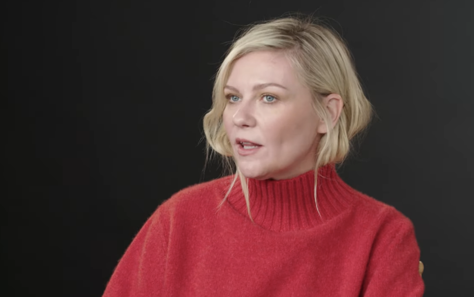 Kristen Dunst in red top speaks in a video titled "Kristen Dunst Breaks Down Her Most Iconic Characters" on YouTube