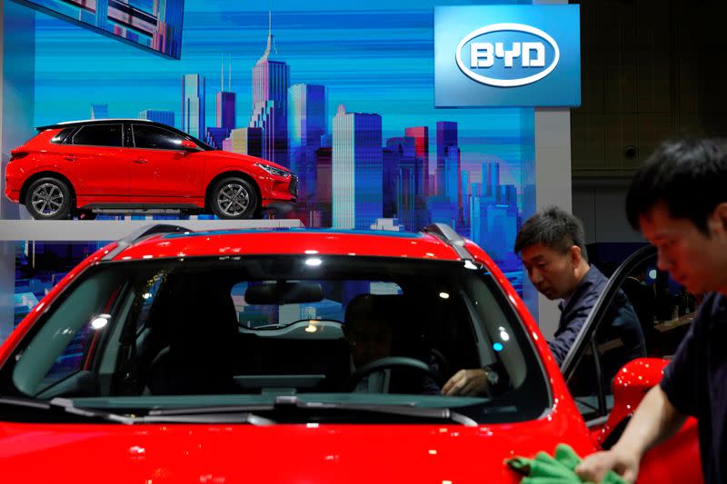 FILE PHOTO: Men clean a BYD electric vehicle (EV) e2 displayed during the media day for Shanghai auto show