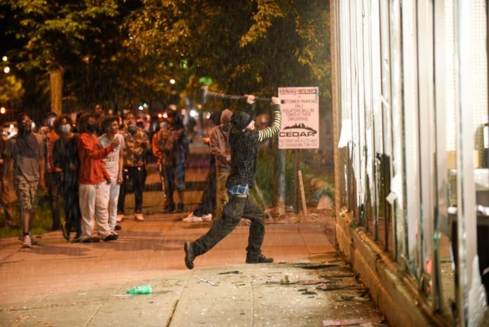 Un joven destroza el escaparate de una tienda de repuestos de automóvil este 28 de mayo en Minneapolis. (Foto: Nicholas Pfosi / Reuters).