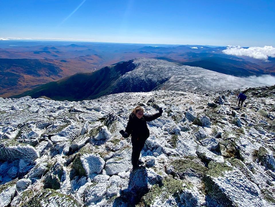 Wide angle shot of a girl standing on the summit of a mountain on a clear day