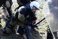 A riot policeman detains a protester during clashes in Karava near the area where the government plans to build a new migrant detention center, on the northeastern Aegean island of Lesbos, Greece, Wednesday, Feb. 26, 2020. Local authorities declared a 24-hour strike on two eastern Greek islands Wednesday to protest government plans to build new migrant detention camps there. (AP Photo/Michael Varaklas)