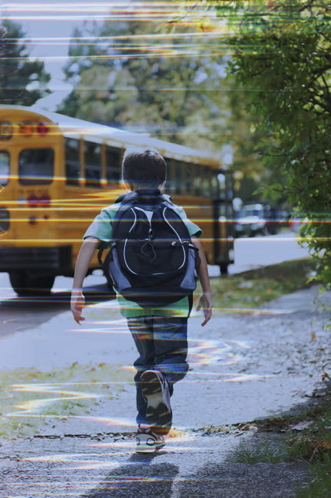 A little boy running toward the school bus