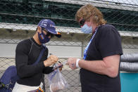 Takuma Sato of Japan signs an autograph for a fan during practice for the Indianapolis 500 auto race at Indianapolis Motor Speedway in Indianapolis, Tuesday, May 18, 2021. (AP Photo/Michael Conroy)