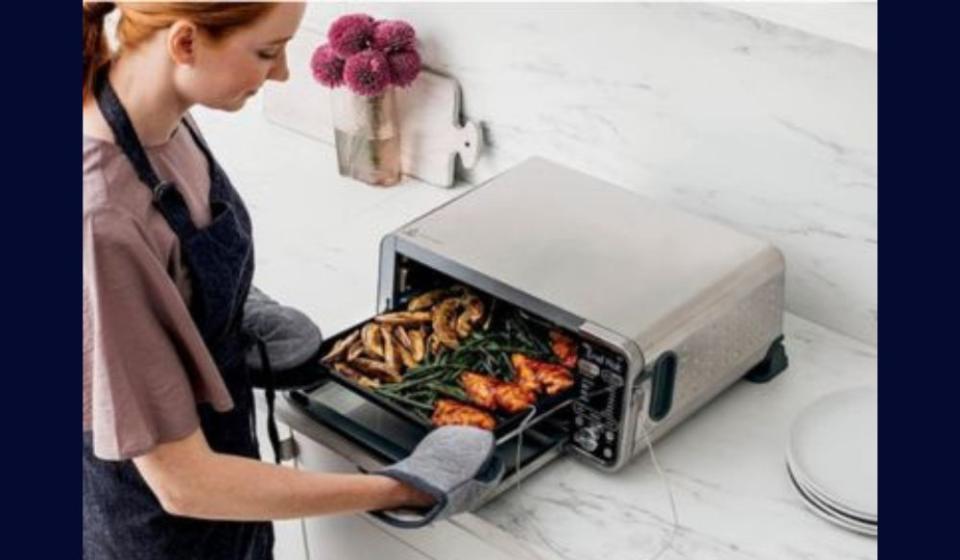 woman using air fryer on kitchen counter