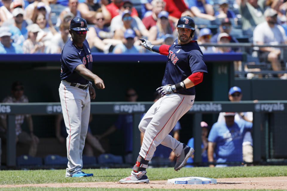 Boston Red Sox third base coach Carlos Febles, left, looks on as J.D. Martinez, right, stops at third base after hitting a triple in the third inning of a baseball game against the Kansas City Royals at Kauffman Stadium in Kansas City, Mo., Sunday, June 20, 2021. (AP Photo/Colin E. Braley)