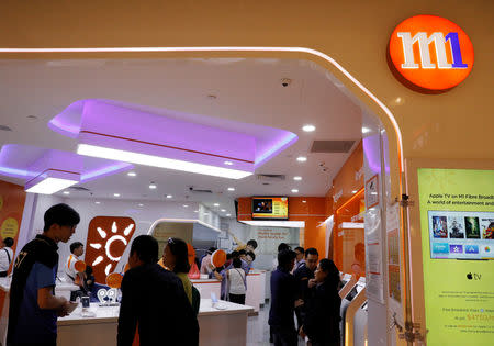 FILE PHOTO: People shop for handsets at an M1 mobile shop in Singapore March 21, 2017. REUTERS/Edgar Su