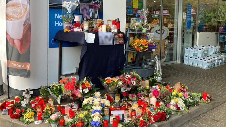 Blumen und Kerzen sind vor der Aral-Tankstelle in Idar-Oberstein aufgestellt.