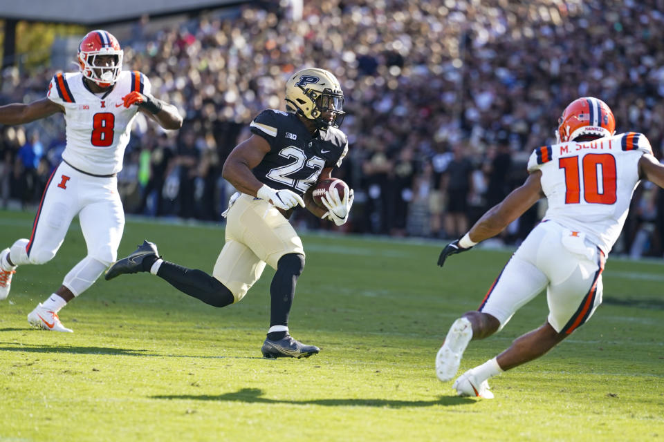 Purdue running back Dylan Downing (22) cuts between Illinois linebacker Tarique Barnes (8) and defensive back Miles Scott (10) on his way to a touchdown during the first half of an NCAA college football game in West Lafayette, Ind., Saturday, Sept. 30, 2023. (AP Photo/Michael Conroy)