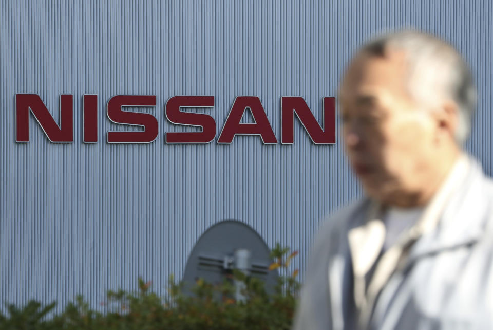 In this Jan. 9, 2019, photo, a man walks past the logo at global headquarters of Nissan Motor Co., Ltd. in Yokohama, near Tokyo. Nissan has lowered its profit forecast for the fiscal year through March as the Japanese automaker, contends with slowing sales and the fallout from the loss of its former chairman, Carlos Ghosn. Nissan Motor Co. said Wednesday, April 24, 2019 it expects to post a 319 billion yen profit ($2.9 billion) for the fiscal year, marking a 22 percent drop from its earlier 410 billion yen ($3.7 billion) profit forecast earlier. (AP Photo/Koji Sasahara)