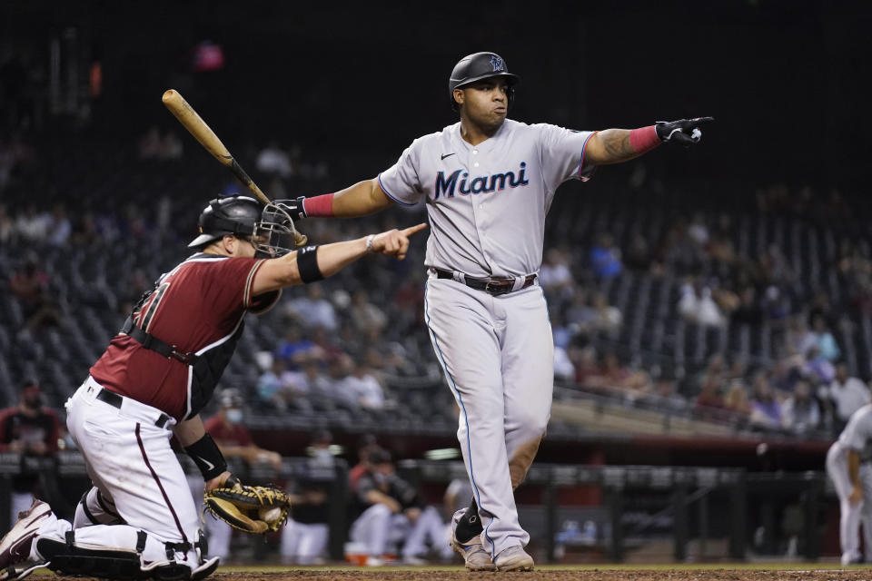 Miami Marlins' Jesus Aguilar, right, and Arizona Diamondbacks catcher Stephen Vogt, left, point to the first base umpire, who ruled that Aguilar went around on a check swing during the ninth inning of a baseball game Wednesday, May 12, 2021, in Phoenix. The Marlins won 3-2. (AP Photo/Ross D. Franklin)