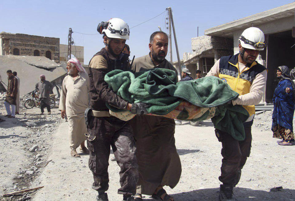 This photo provided by the Syrian Civil Defense group known as the White Helmets, shows members of the Syrian Civil Defense workers carrying a victim after a deadly airstrike hit a market killing several people in the village of Ras el-Ain, in the northwestern province of Idlib, Syria, Tuesday, May 7, 2019. Opposition activists say government forces have intensified their bombardment of rebel-held towns and villages in northwestern Syria. (Syrian Civil Defense White Helmets via AP)